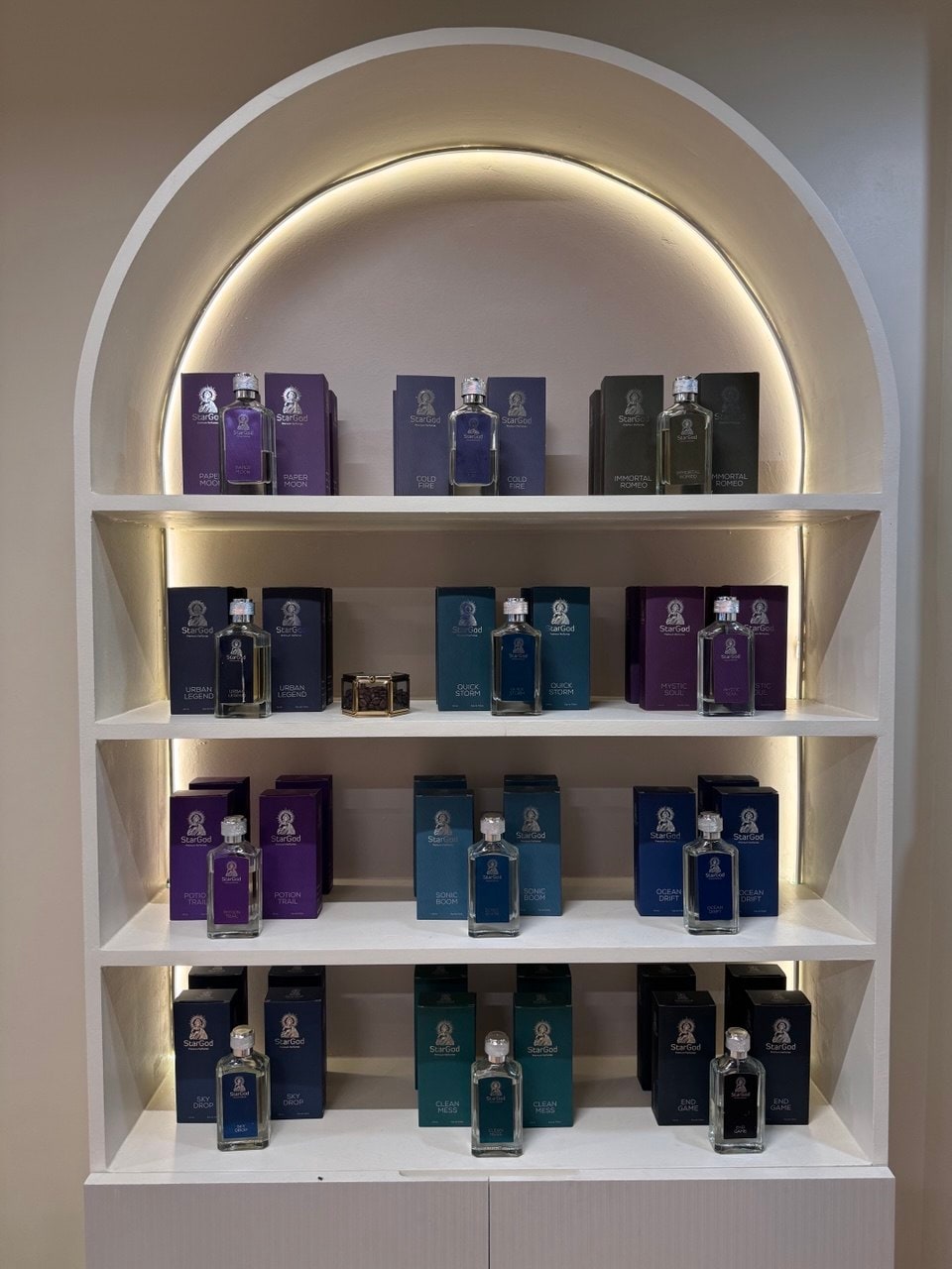 A second alcove of cooler-toned bottles — blues and purples — under a soft halo of light.