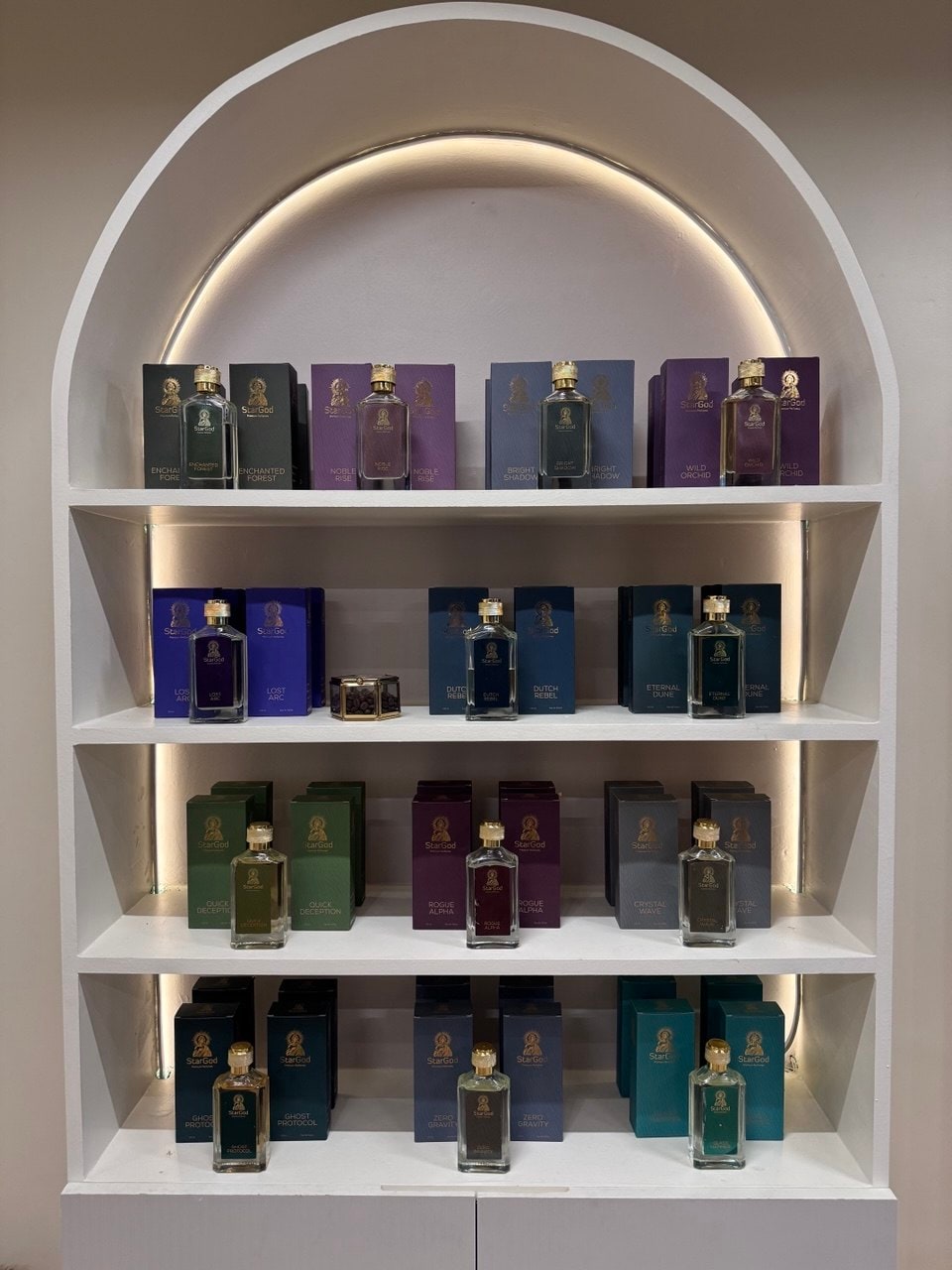 Green and dark fragrances on a third alcove shelf, lit from above.