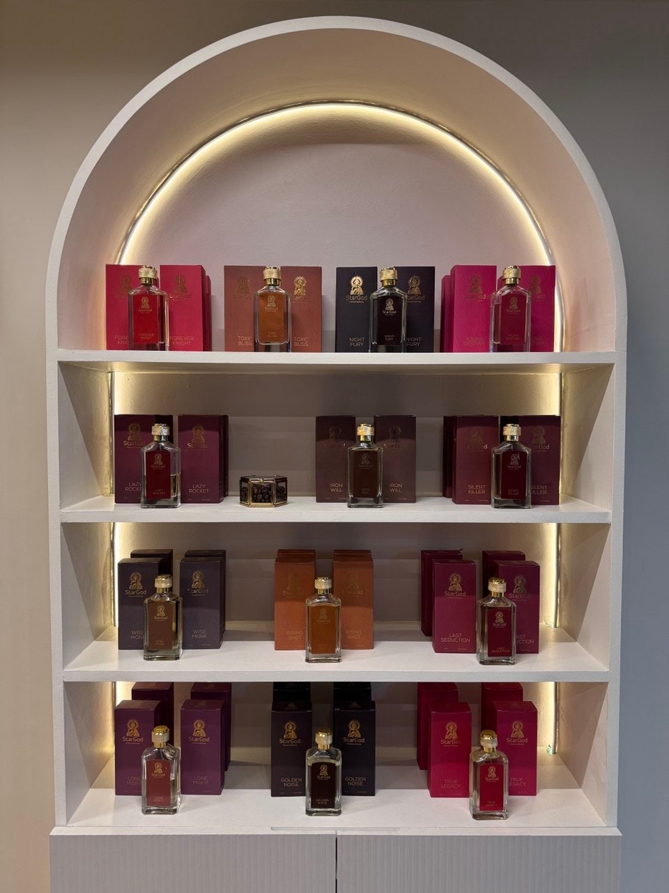 Warm-toned arched alcove with reds, ambers, and burgundies — the boutique's signature shelving.