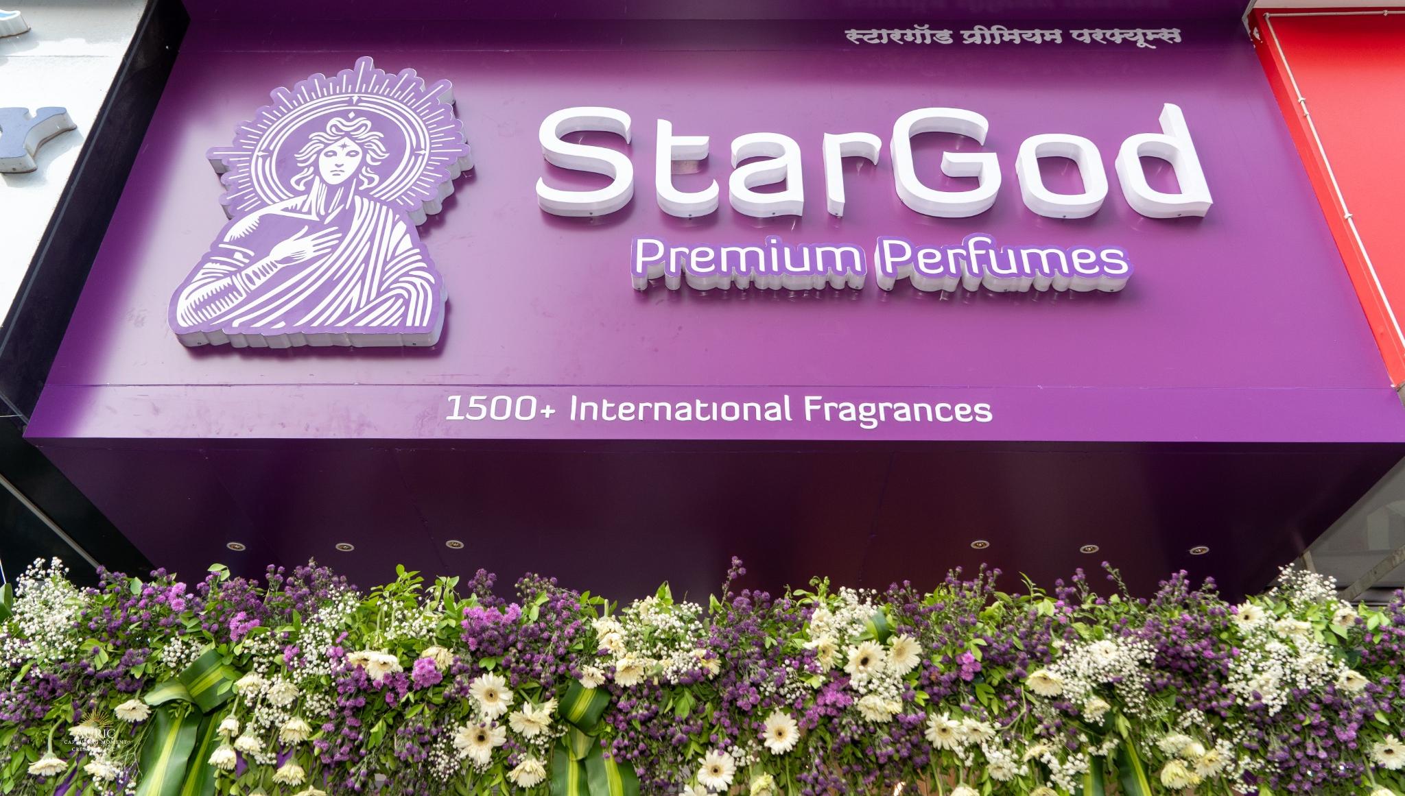 Close-up of the StarGod boutique signboard — haloed wordmark on a deep purple panel, with Devanagari script and the line '1500+ International Fragrances'.