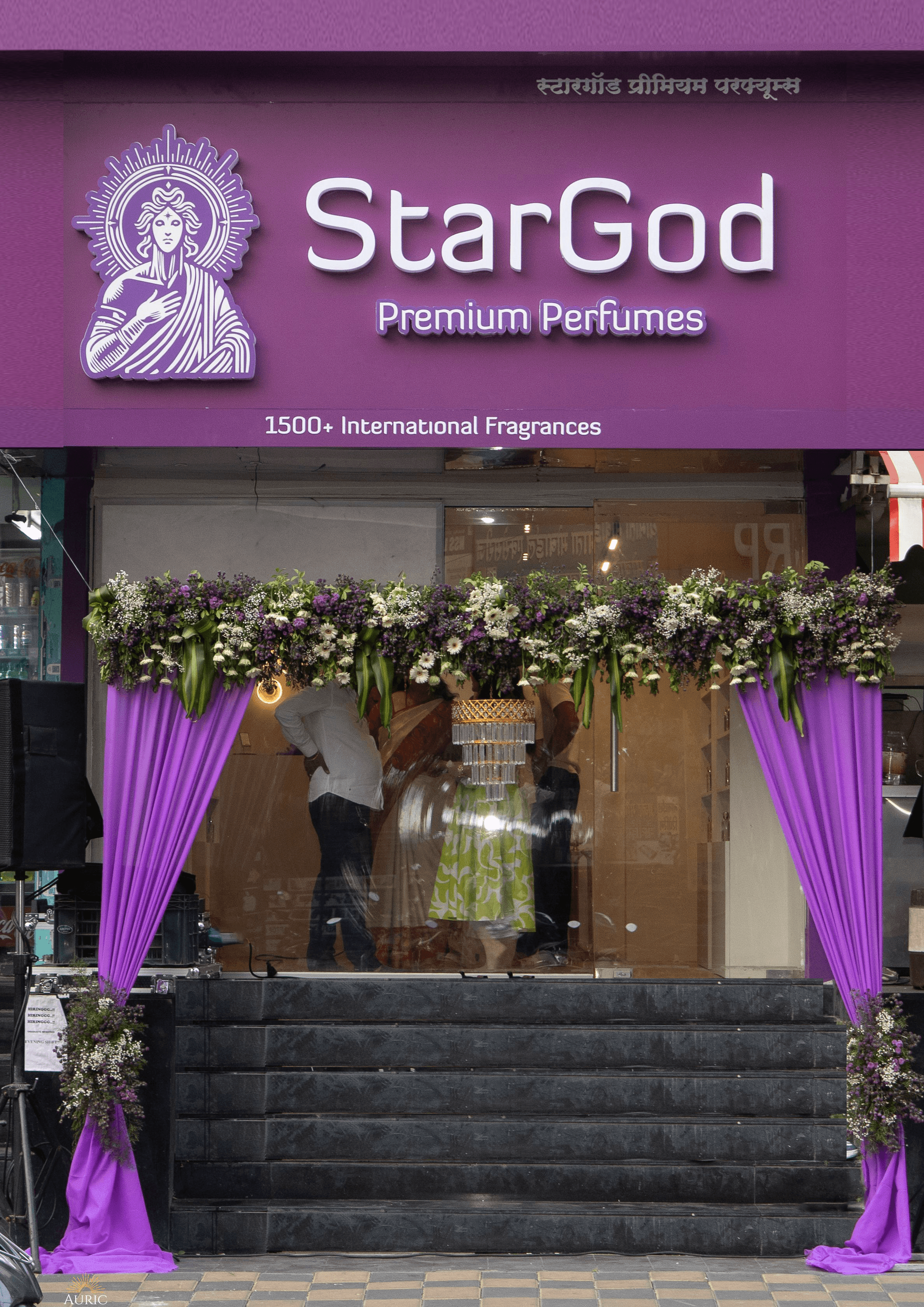 The StarGod Premium Perfumes storefront on Tilak Road — purple signboard with the haloed wordmark and '1500+ International Fragrances', a glass entrance under a floral arch with deep purple drape curtains framing the steps.